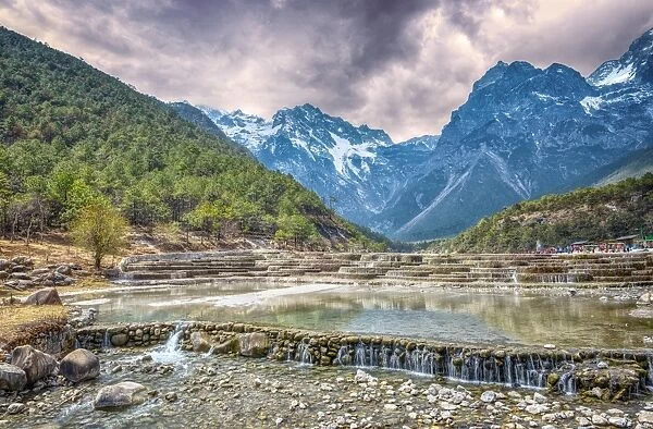 HDR image of cascading falls at Baishuihe, or White Water River with Jade Dragon Snow Mountain, Lijiang, Yunnan, China, Asia