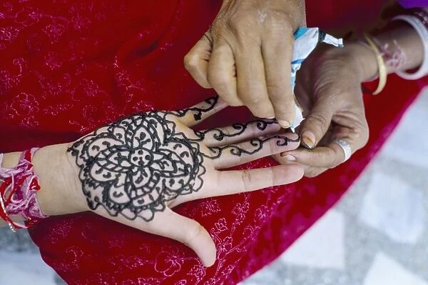 Henna designs being applied to a womans hand