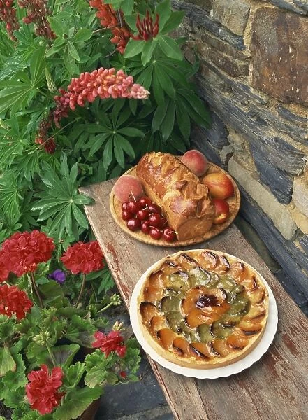 High angle view of still life of brioche and fruit tart patisserie outside in a garden with geraniums and lupins