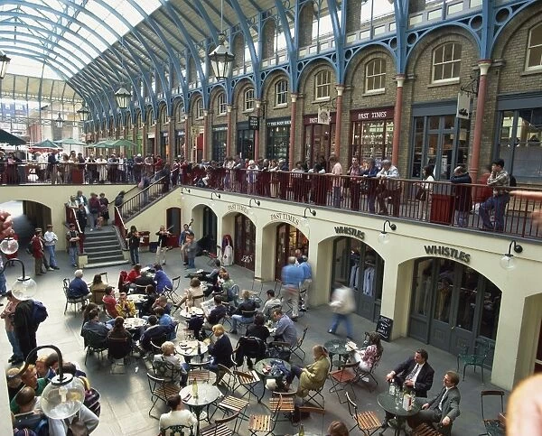 High angle view of people sitting at tables at cafes in the interior of the covered market place at Covent Garden, London, England, United