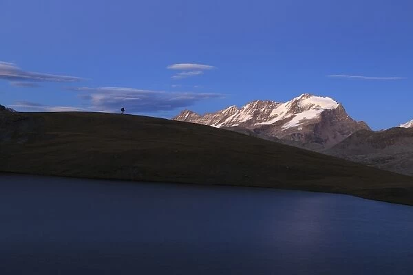Hiker admires sunset on Rossett Lake at an altitude of 2709 meters, Gran Paradiso National Park
