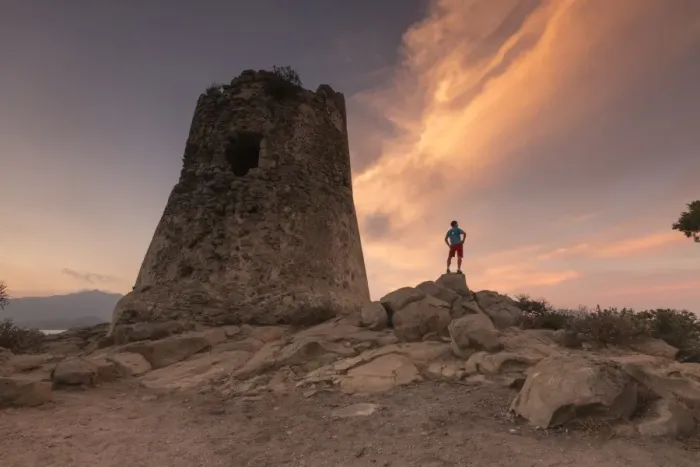 Framed Print : Hiker admires sunset from the stone tower overlooking the bay, Porto Giunco, Villasimius Framed Print : Hiker admires sunset from the stone tower overlooking the bay, Porto Giunco, Villasimius