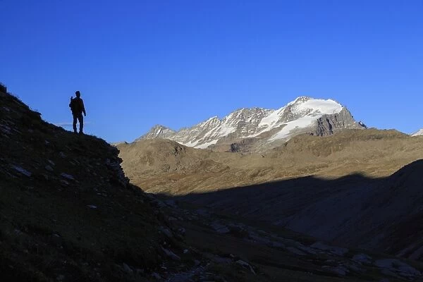 Hiker admires the view of Alpi Graie (Graian Alps) landscape, Gran Paradiso National Park