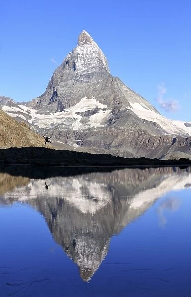 Hiker admiring the Matterhorn reflected in Lake Stellisee, Zermatt, Canton of Valais