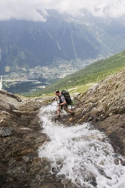 Hiker crossing a stream above Chamonix Valley, Rhone Alps, France, Europe