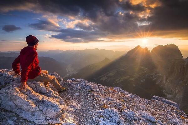 Hiker looks sunset from Piz Pordoi. Fassa Valley, Trentino, Dolomites, Italy, Europe