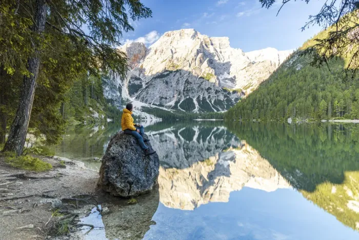 Framed Print : Hiker man enjoying sunrise sitting on rocks on shore of Lake Braies (Pragser Wildsee Framed Print : Hiker man enjoying sunrise sitting on rocks on shore of Lake Braies (Pragser Wildsee