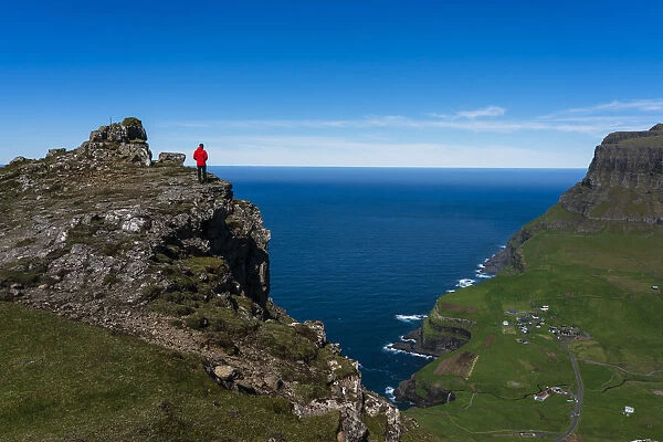 Hiker on The Postmans Trail to the village of Gasaldur, Vagar Island, Faroe Islands, Denmark, Europe