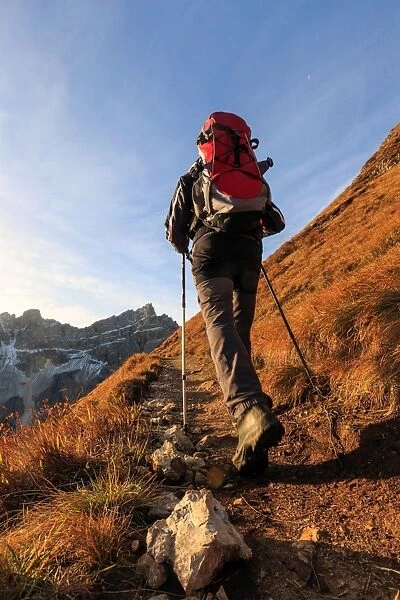 Hiker proceeds toward the group Forcella De Furcia at sunrise, Funes Valley, South Tyrol