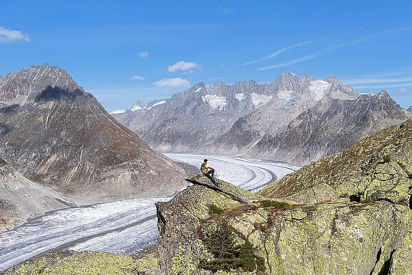 Hiker on top of a rock enjoying the view of the Aletsch Glacier and alpine mountains with snow, Aletsch Glacier, Bettmerhorn, UNESCO World Heritage Site, Valais canton, Switzerland, Europe