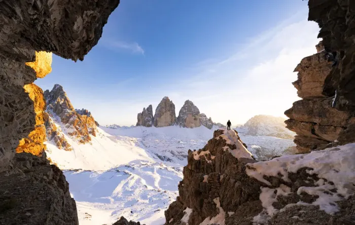 Framed Print : Hiker on rocks admiring Tre Cime di Lavaredo and Monte Paterno covered with snow Framed Print : Hiker on rocks admiring Tre Cime di Lavaredo and Monte Paterno covered with snow