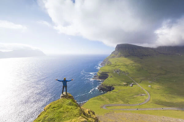 Hiker on top of rocks, Gasadalur, Vagar Island, Faroe Islands, Denmark, Europe