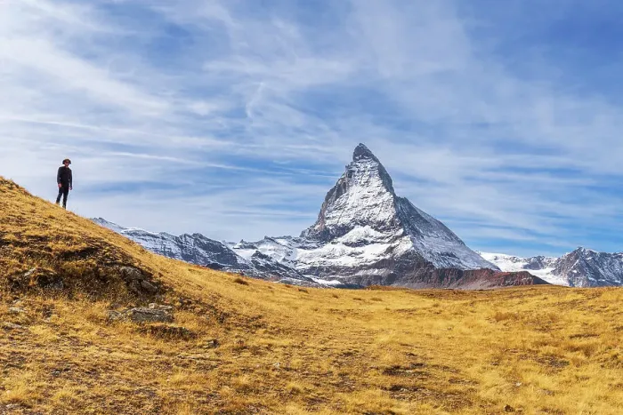 Framed Print : Hiker stands in front of the iconic shape of Matterhorn among yellow grasses, Riffelalp, Zermatt, Valais Canton, Swiss Alps, Switzerland, Europe