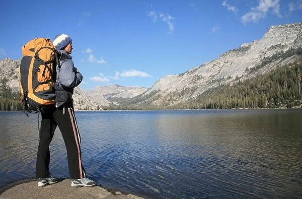 A hiker takes in the view on the shore of Tenaya Lake, in the Tuolumne Meadows