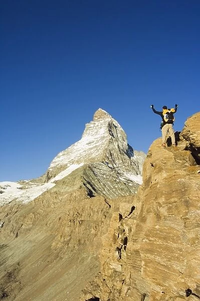 Hiker on trail celebrating at the sight of the Matterhorn