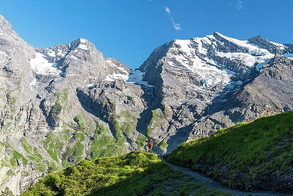 Hiker walks the summer trail surrounded by Swiss glacier, Oeschinensee, Kandersteg, Bern Canton, Switzerland, Europe