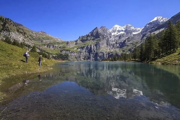 Hikers admire Lake Oeschinensee, Bernese Oberland, Kandersteg, Canton of Bern, Switzerland