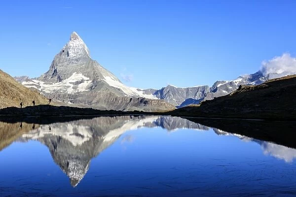 Hikers admiring the Matterhorn reflected in Lake Stellisee, Zermatt, Canton of Valais
