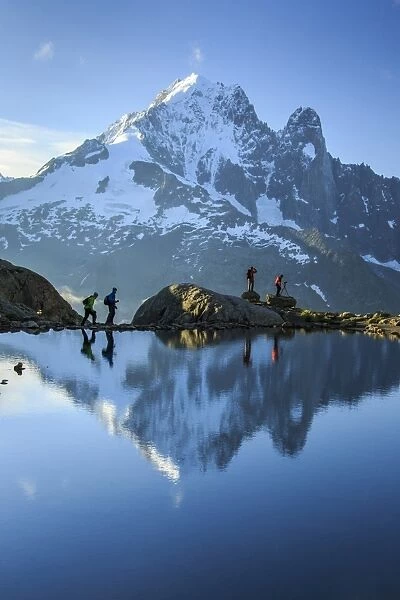 Hikers on the shores of Lac de Cheserys, with Aiguille Verte reflected at dawn, Chamonix