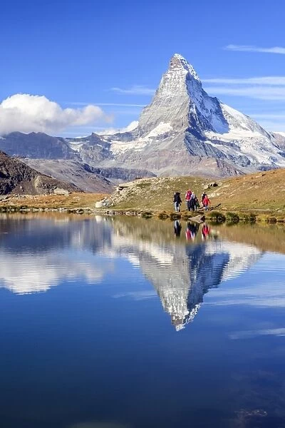Hikers walking on the path beside the Stellisee with the Matterhorn reflected, Zermatt