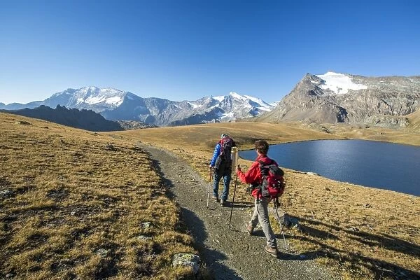 Hikers wallking along Rosset Lake, Gran Paradiso National Park, Alpi Graie (Graian Alps)