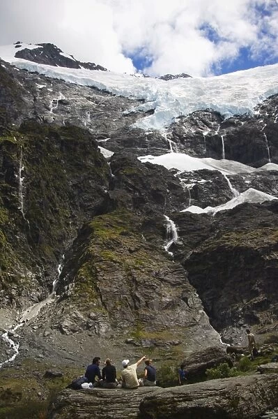 Hikers watch water cascading off Rob Roy Glacier in