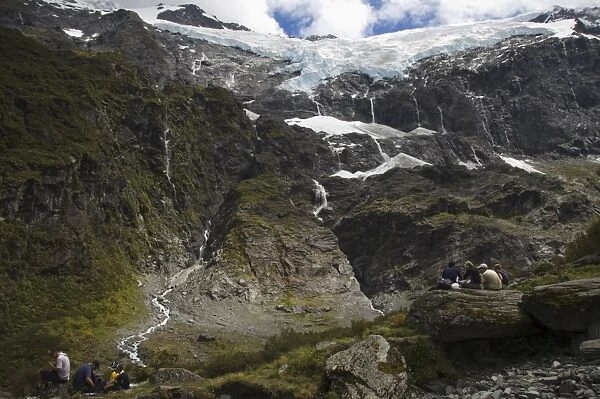 Hikers watch water cascading off Rob Roy Glacier