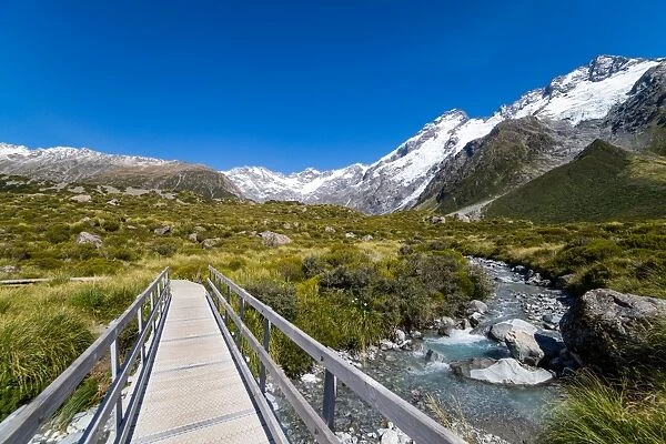 A hiking trail crosses wooden bridge over a creak high up in the mountains, South Island