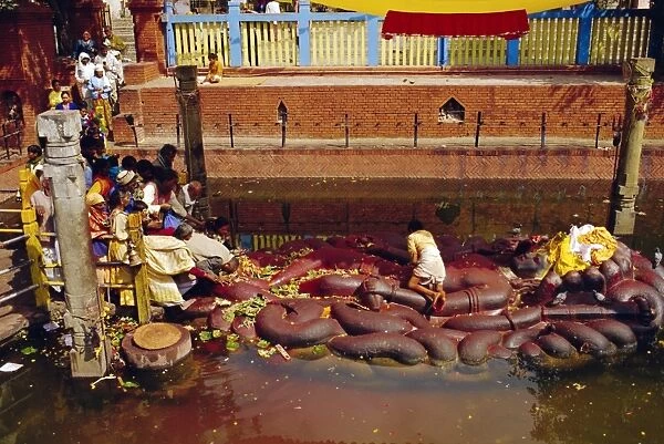Hindus praying and giving offerings to a giant statue of Vishnu