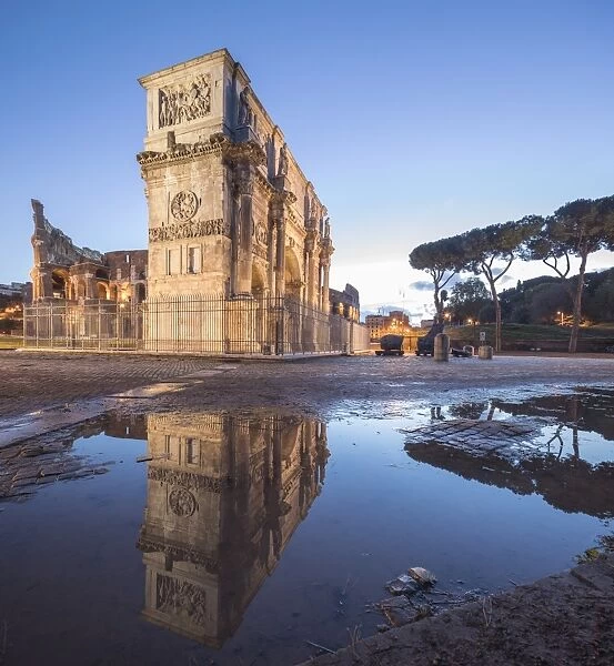 The historical Arch of Constantine reflected in a puddle at dusk, Rome, Lazio, Italy