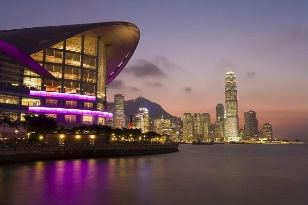 Hong Kong Convention and Exhibition centre illuminated at dusk with the International Finance Centre building and financial district in the background, Hong Kong