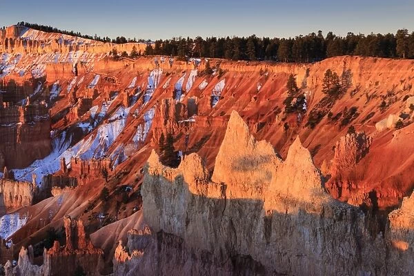 Hoodoos, rim and snow lit by strong dawn light, Queens Garden Trail at Sunrise Point, Bryce Canyon National Park, Utah, United States of America, North America