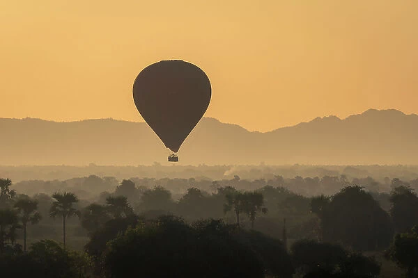 Hot-air balloon at sunrise against mountains, Bagan (Pagan), Myanmar (Burma), Asia