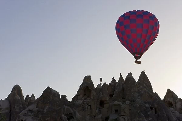 Hot air balloon taking off with tourists on board for a flight over the famous volcanic tufa rock formations around Goreme, Cappadocia, Anatolia, Turkey, Asia