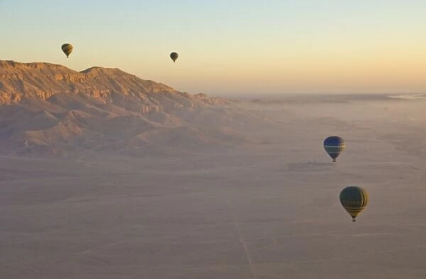 Hot air balloons on an excursion flying over the desert early morning at dawn