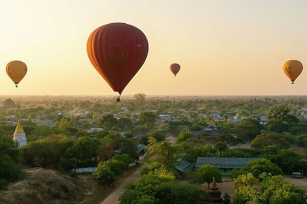 Hot-air balloons at sunrise over village near Bagan (Pagan), Myanmar (Burma), Asia