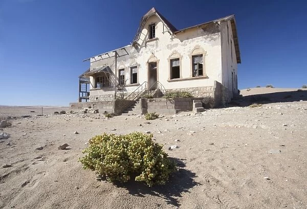 House slowly being reclaimed by the desert in the abandoned former German diamond mining town of Kolmanskop on the edge of the Namib Desert, Forbidden Diamond Area near Luderitz, Namibia, Africa