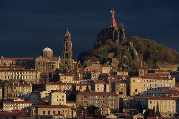 Houses and churches overlooked by a hilltop statue of the Virgin and child at Le Puy