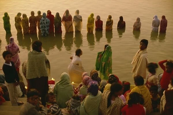 Hundreds of women gather in rows along river front, defying the cold, to welcome the rising sun god