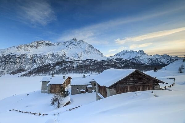 Huts and mountains covered in snow at sunset, Spluga Maloja, Canton of Graubunden