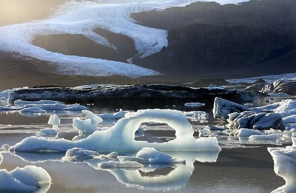 Ice arch among icebergs floating on Fjallsarlon lagoon, near Jokulsarlon, South Iceland