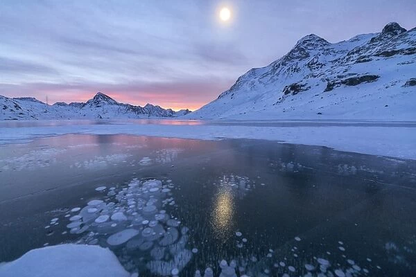 Ice bubbles frame the frozen Lago Bianco at dawn, Bernina Pass, canton of Graubunden