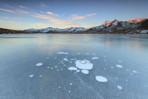 Ice bubbles on the frozen surface of Andossi Lake at sunrise, Spluga Valley, Valtellina