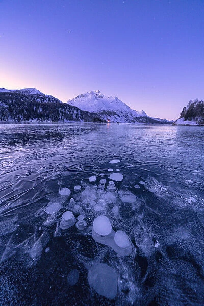 Ice bubbles trapped in Lake Sils with Piz Da La Margna in background at dawn, Engadine