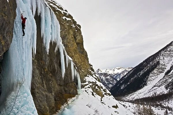An ice climber ascending a frozen cascade in the Fournel Valley, Ecrins Massif, France