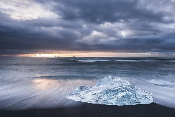 Iceberg at sunrise on Jokulsarlon Beach, a black volcanic sand beach in South East Iceland