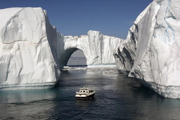 Icebergs in Disko Bay, natural arch and motorboat, UNESCO World Heritage Site, Ilulissat (Jakobshavn), Greenland, Denmark, Polar Regions