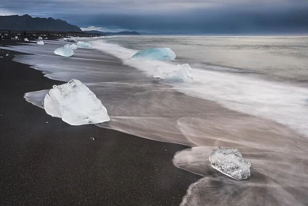 Icebergs at sunrise on Jokulsarlon Beach, a black volcanic sand beach in South East Iceland