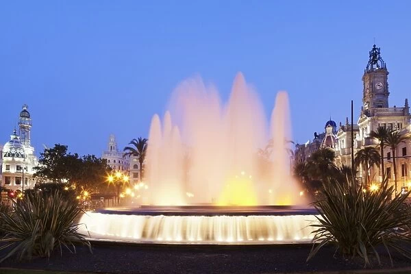 Illuminated fountain on Plaza del Ayuntamineto with town hall at dusk, Valencia, Comunidad Valencia, Spain, Europe
