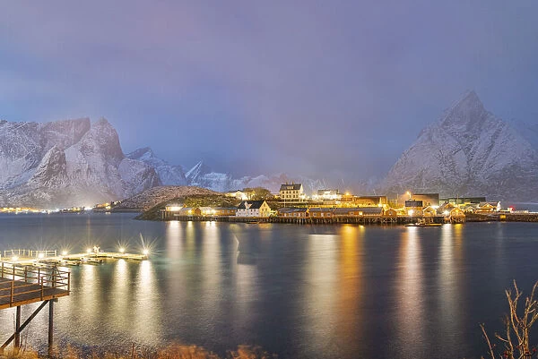 Illuminated Rorbu and houses in night fog during the cold winter, Sakrisoy, Reine, Nordland county, Lofoten Islands, Norway, Scandinavia, Europe